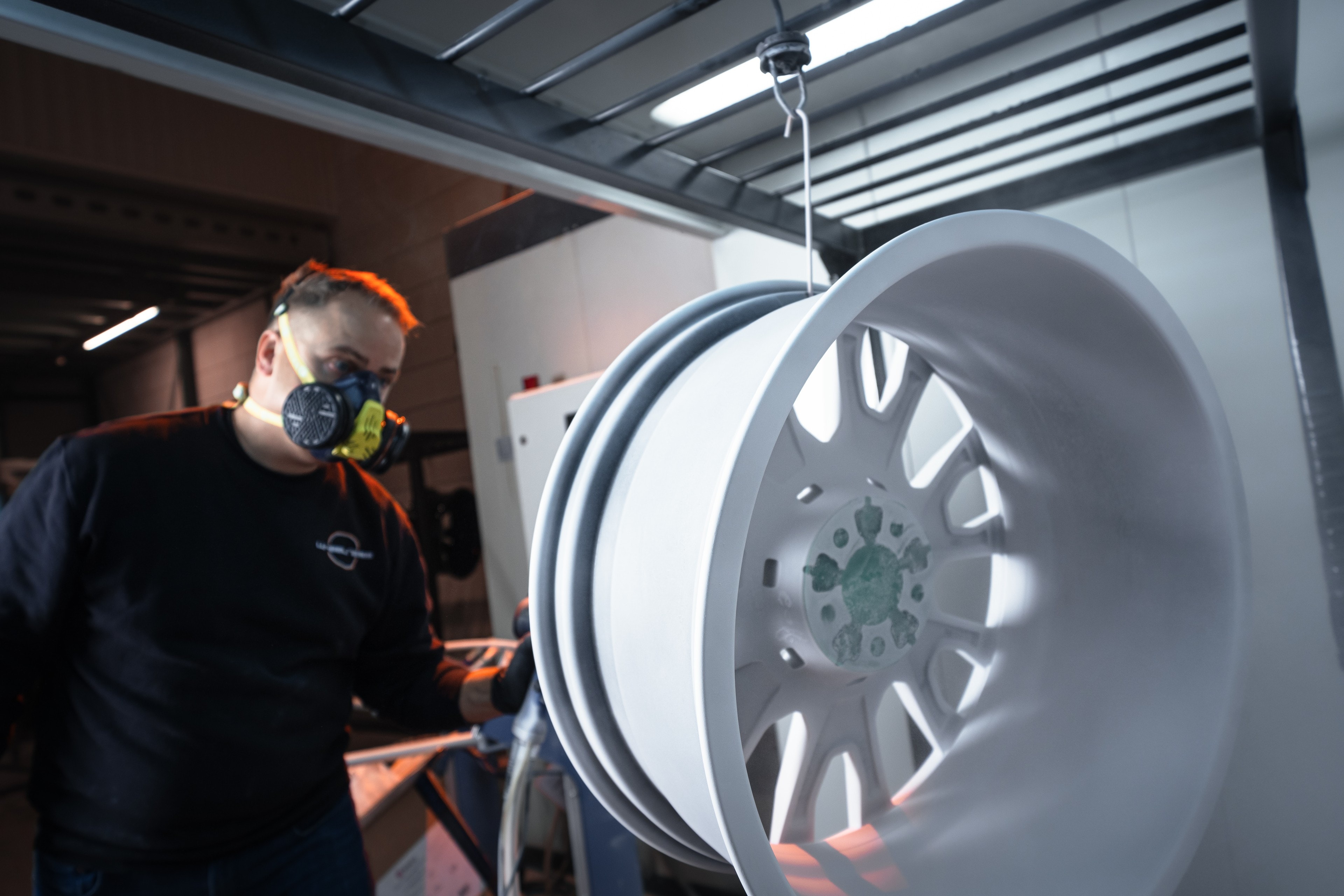 Koen met mondkapje bij een wit gecoate velg in de spuitcabine