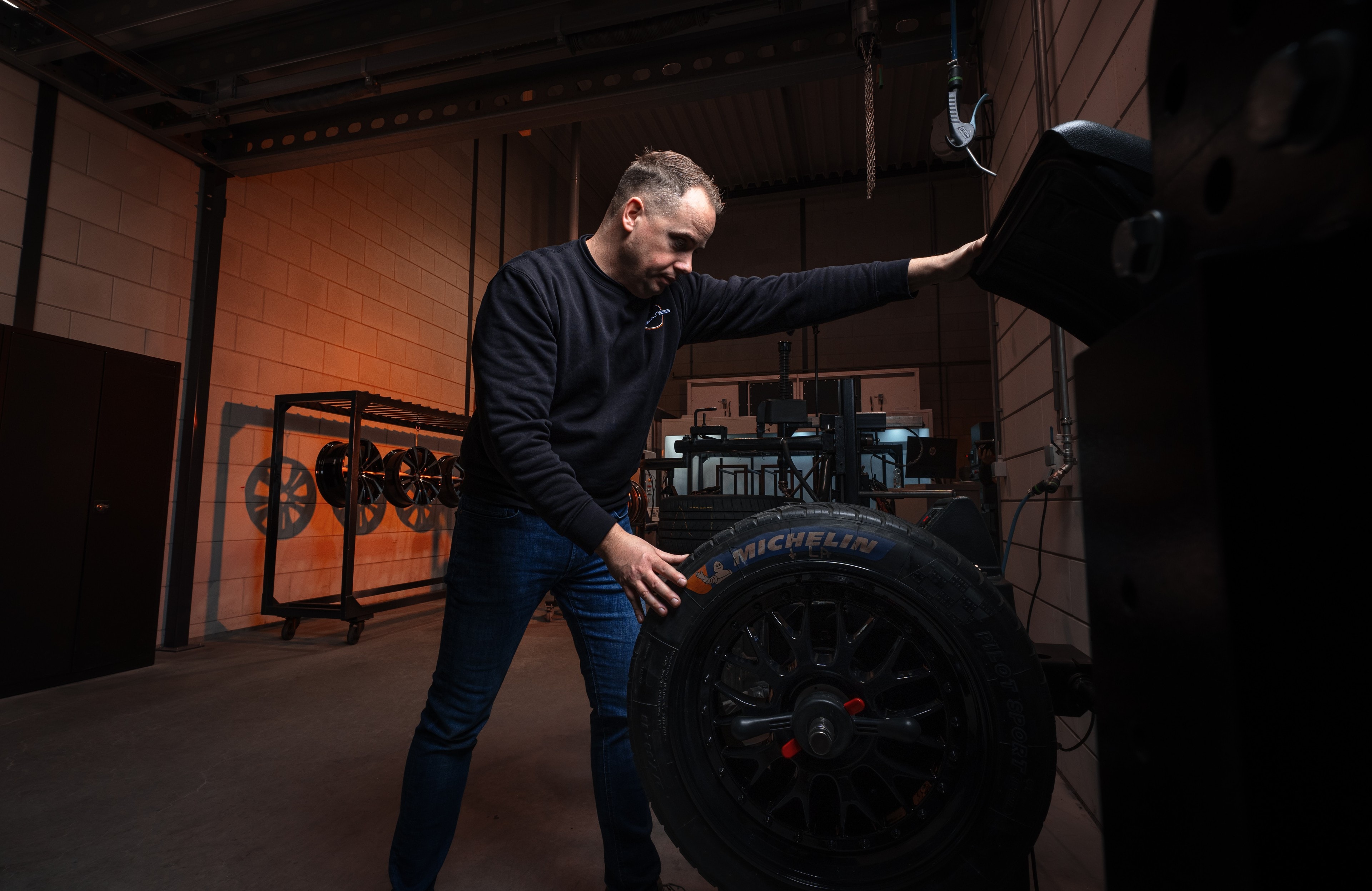 Koen zet een wiel met band op de machine in de werkplaats